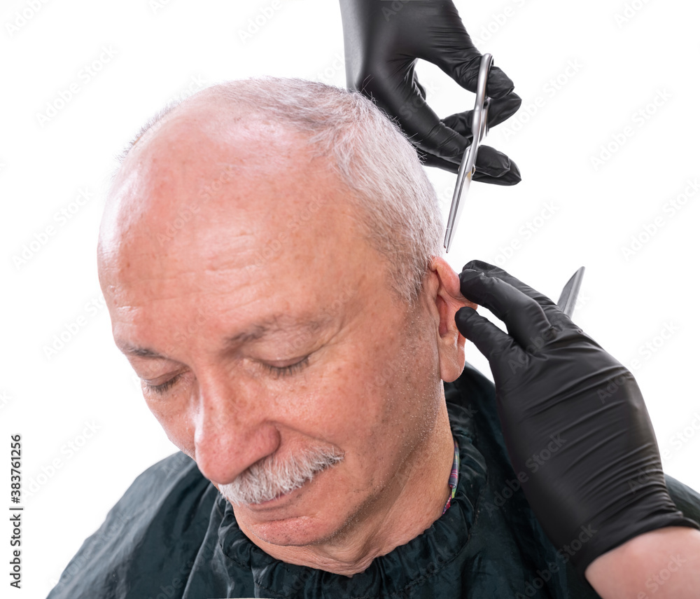 Closeup image of senior man in barber shop.Barber cutting hair with scissors over white background