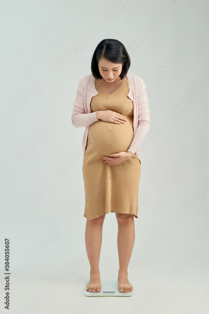 Pregnant woman standing on scales at home. Pregnancy weight gain concept