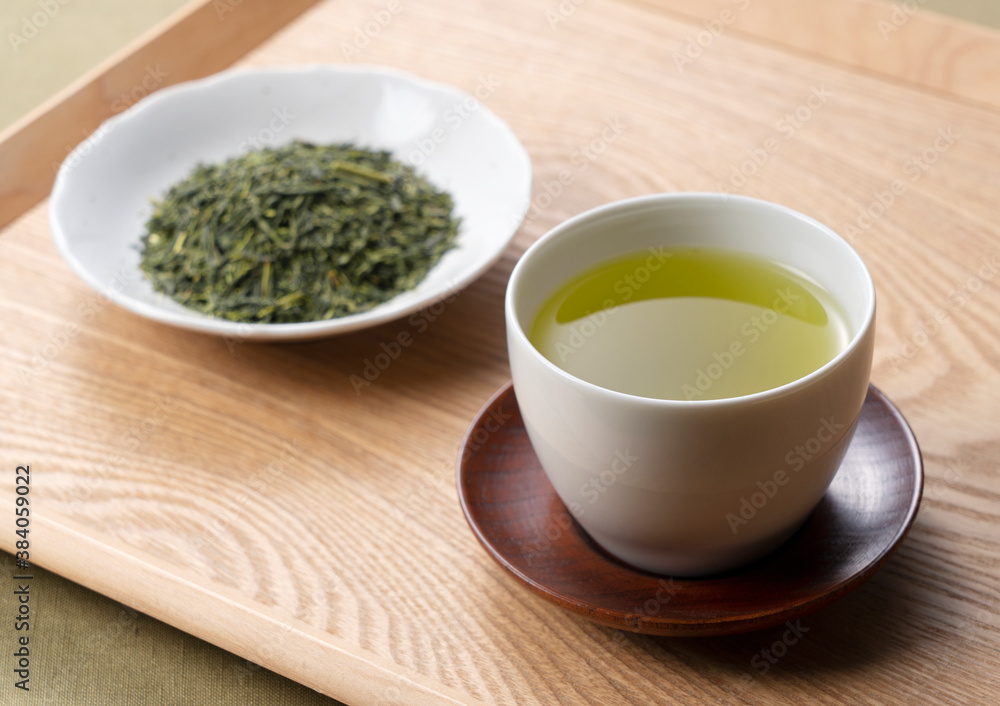 Green tea and tea leaves on a wooden tray