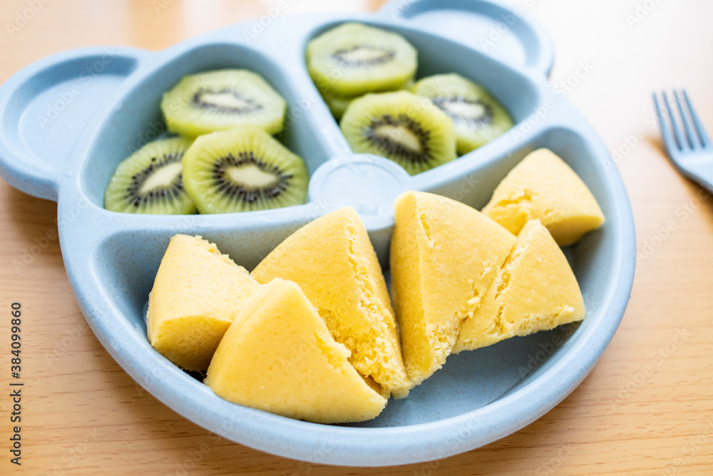 A plate of baby nutrition breakfast with millet cakes and kiwi