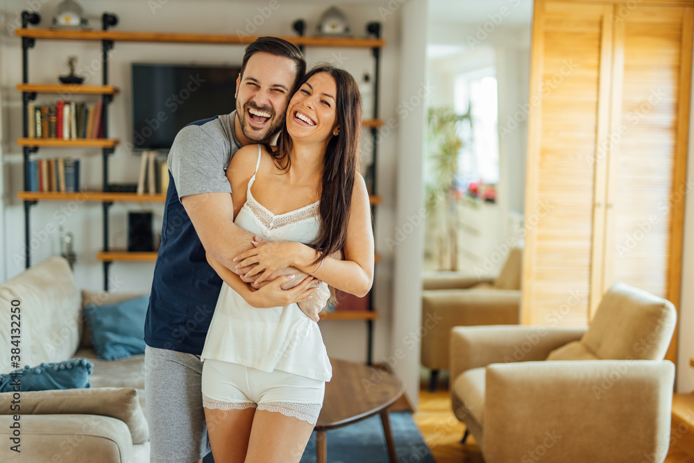 Portrait of a cute couple in pajamas hugging and laughing.