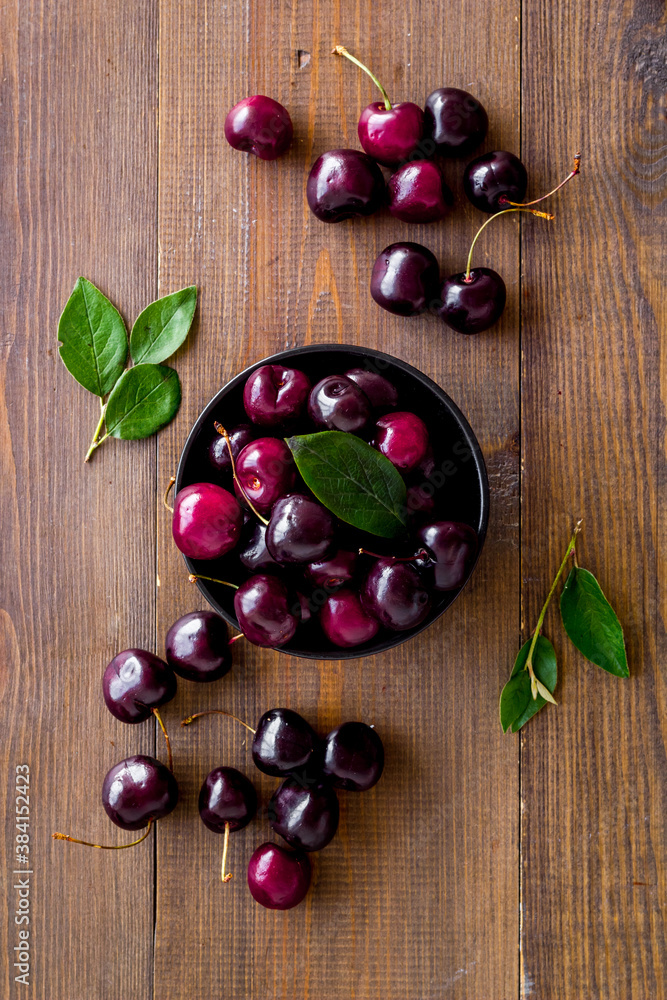 Plate of ripe red cherries with leaves, top view