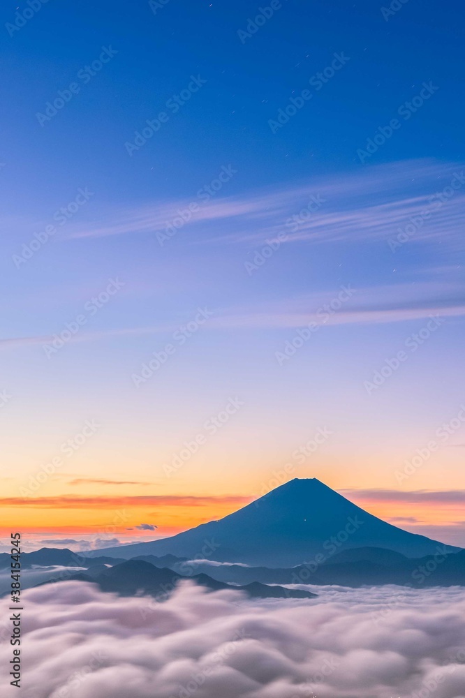 夏季富士山的山峰在日出时耸立在云层和天空的光芒之上