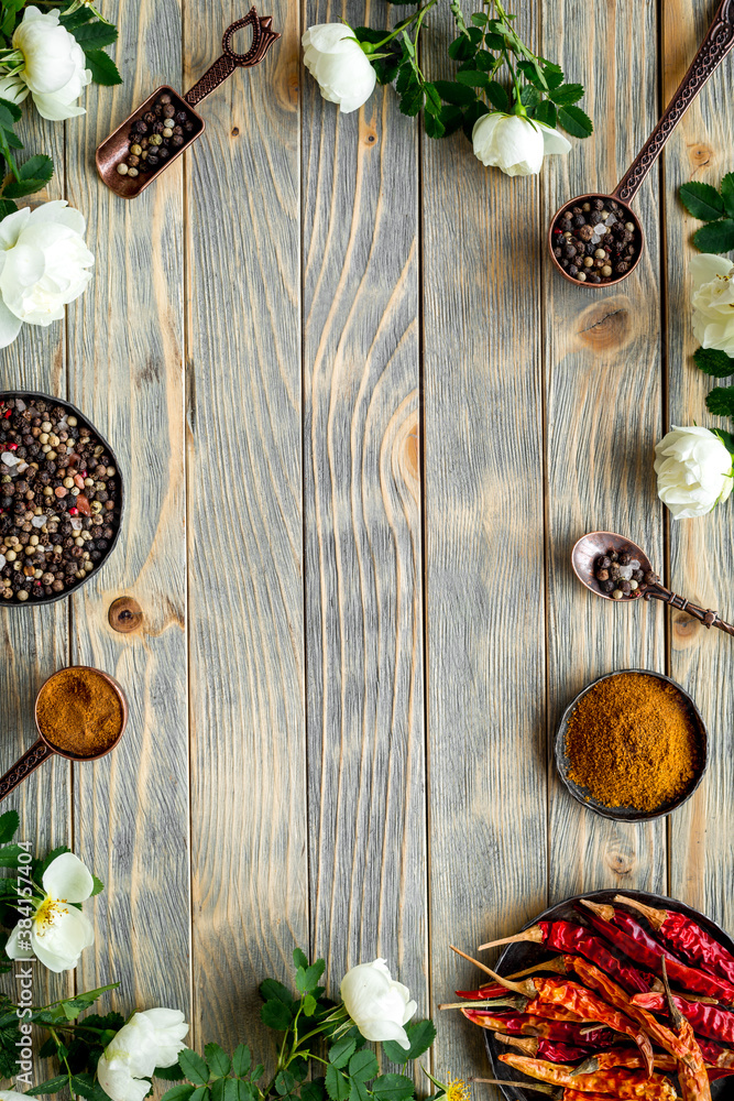 Mix of spices in metal spoons and bowls, flat lay