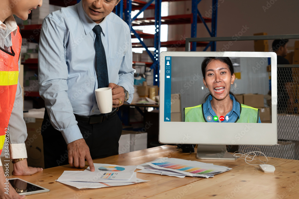 Warehouse staff talking on video call at computer screen in storage warehouse . Online software tech