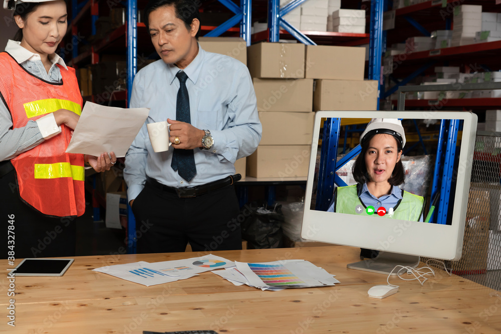 Warehouse staff talking on video call at computer screen in storage warehouse . Online software tech