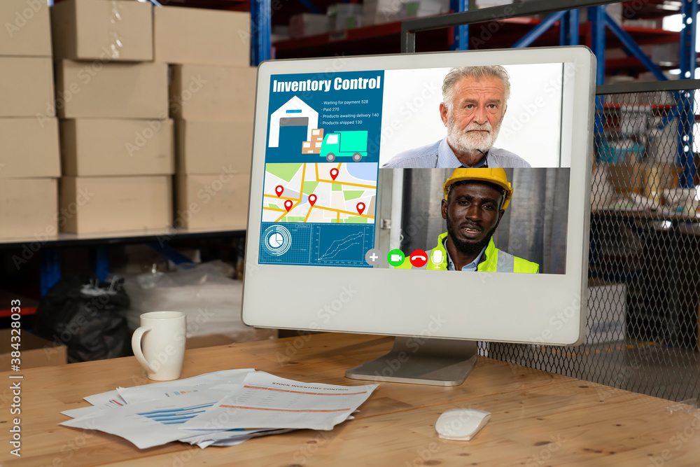 Warehouse staff talking on video call at computer screen in storage warehouse . Online software tech