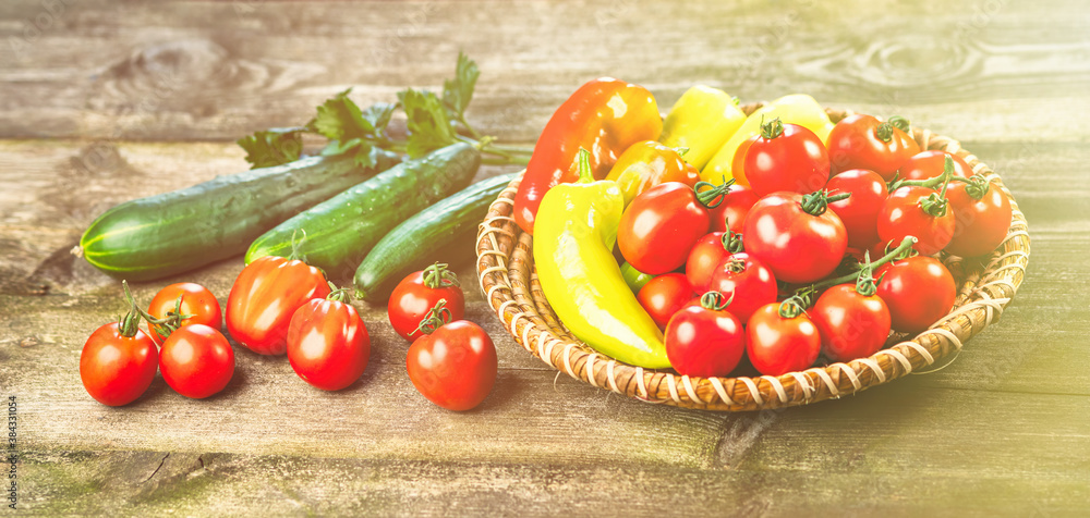 Harvest of fresh ripe vegetables on wooden table and in rod bowl - pepper, tomato, cucumber, celery 