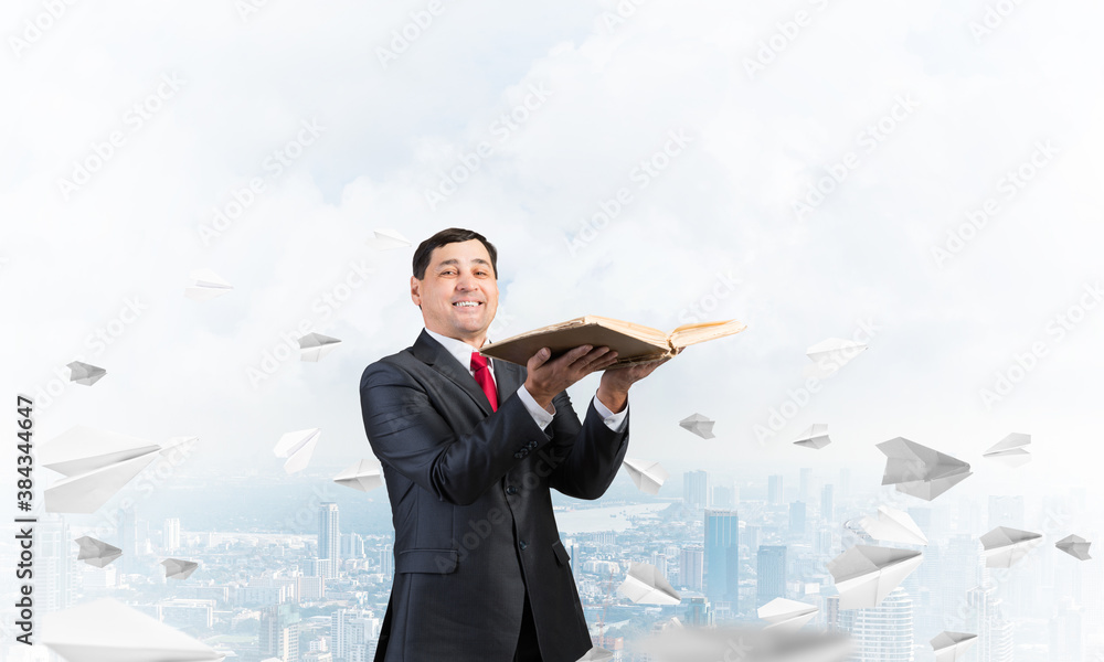 Happy businessman holding open old book