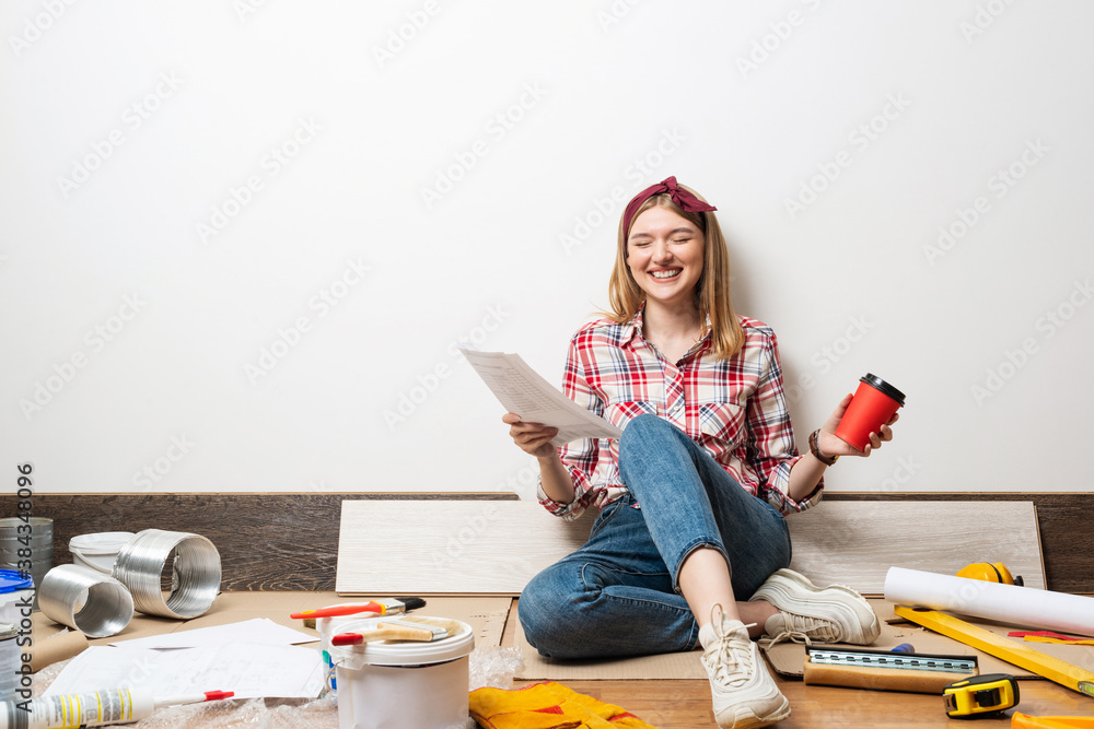 Laughing girl sitting on floor with blueprint