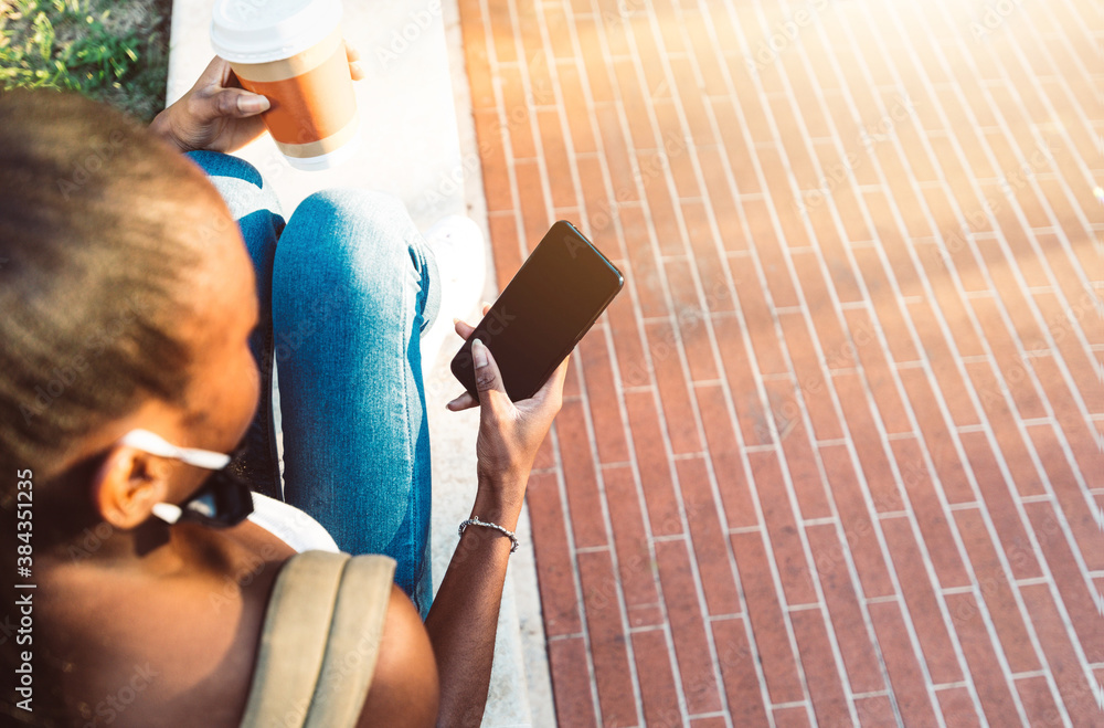 Millennial girl with face mask sitting in the city using mobile smart phone outdoor - Female student