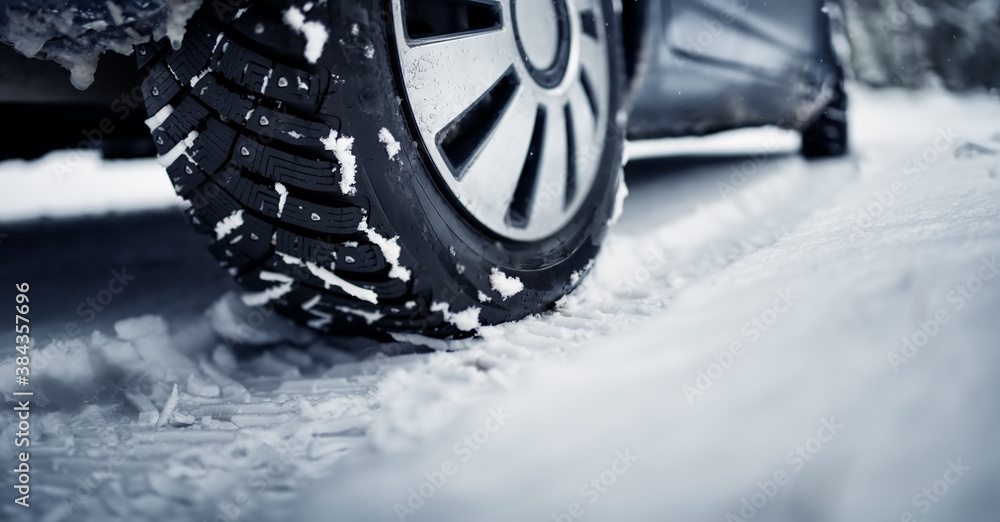 Closeup of the car tire on winter road covered with snow