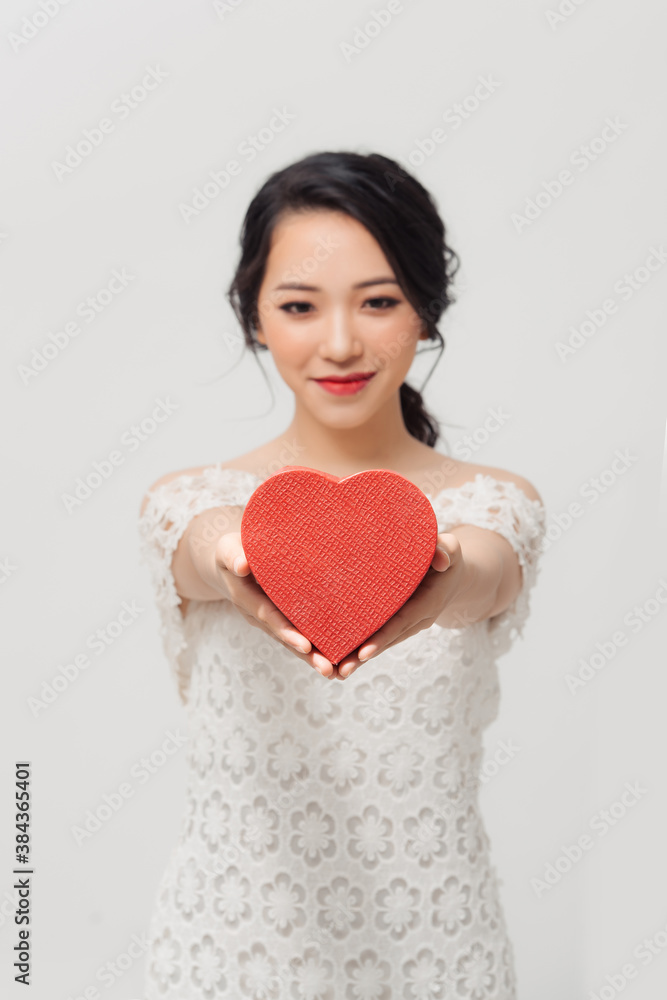 Portrait of young beautiful Asian girl holding love gift box over white background.