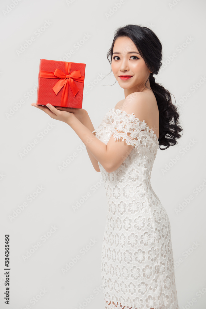 Happy beautiful young Asian woman holding gift box isolated over white background.