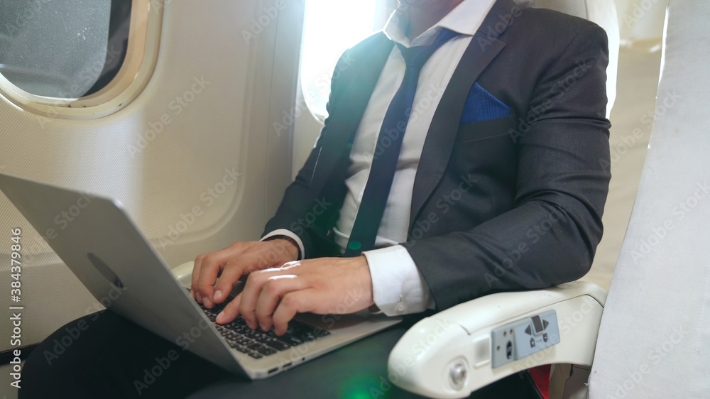 Young businessman using laptop computer in airplane . Business trip travel concept .