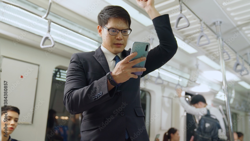 Businessman using mobile phone on public train . Urban city lifestyle commuting concept .