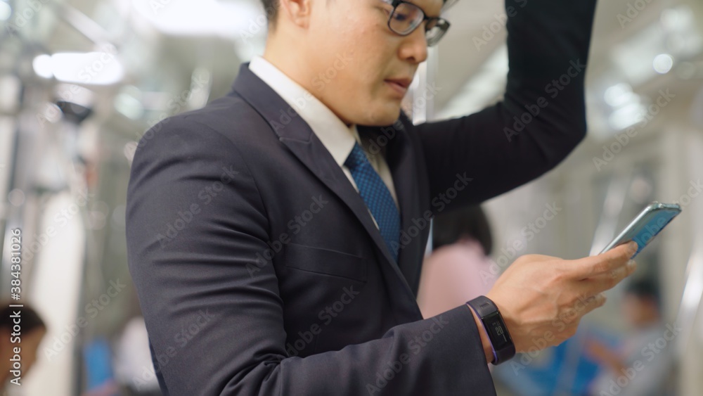 Businessman using mobile phone on public train . Urban city lifestyle commuting concept .