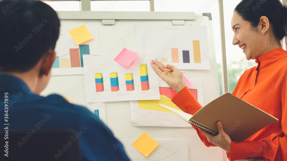 Young woman explains business data on white board in casual office room . The confident Asian busine