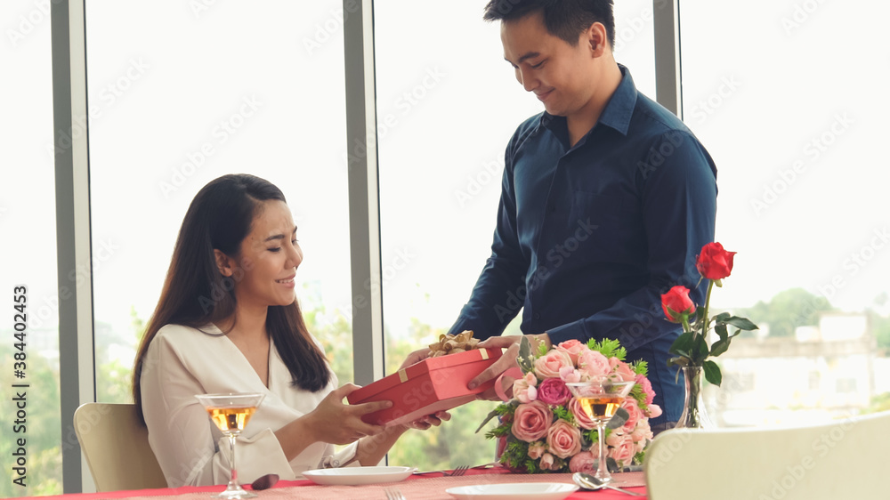 Romantic couple giving gift to lover at restaurant . Happy couple lifestyle .