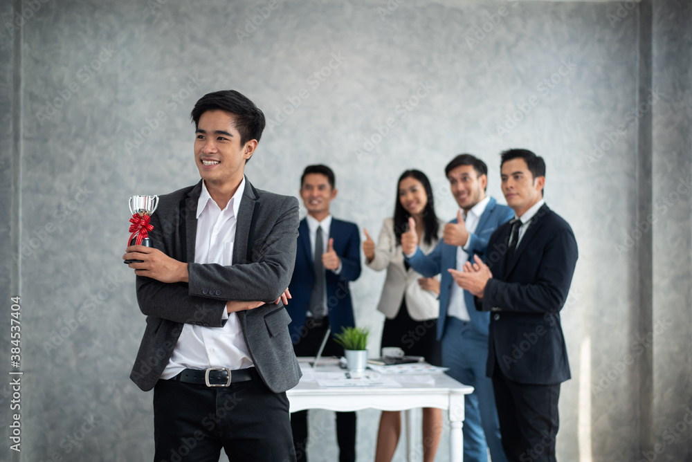 Businessman holding up a winning trophy Many hands applauding behind, Business concept