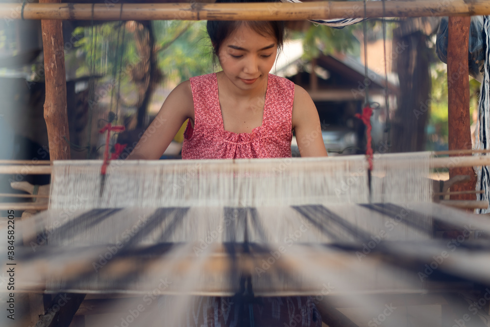 Young women weaving with traditional Thai weaving machine