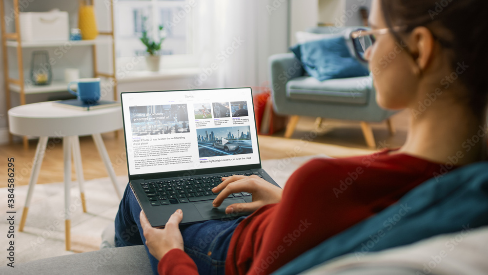 Young Woman at Home Is Using Laptop Computer for Scrolling and Reading News about Technological Brea