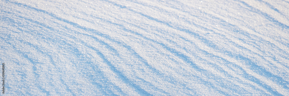 Beautiful winter background with snowy ground. Natural snow texture. Wind sculpted patterns on snow 