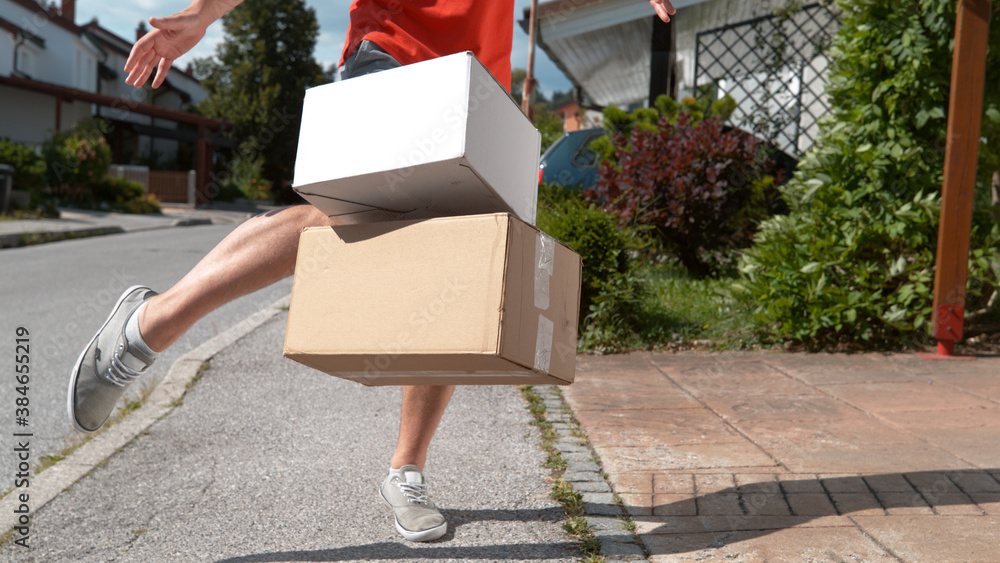 CLOSE UP: Unrecognizable delivery guy drop kicks package into someones driveway