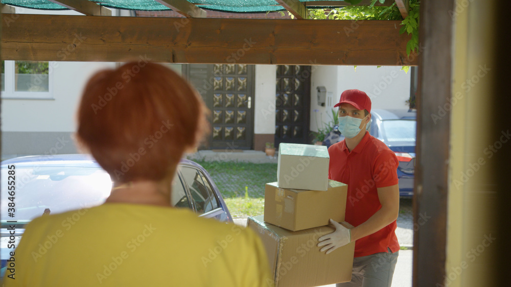 CLOSE UP: Young courier brings packages to elderly lady standing on her doorstep