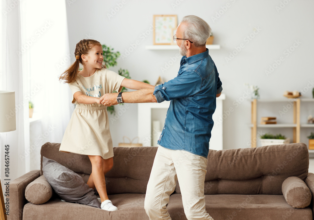 Grandfather dancing with granddaughter at home.