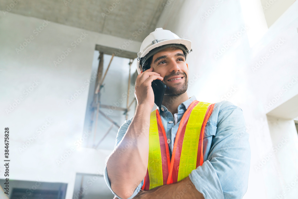 portrait of young caucasian male engineer wearing uniform and hard hat hand use smartphont communica