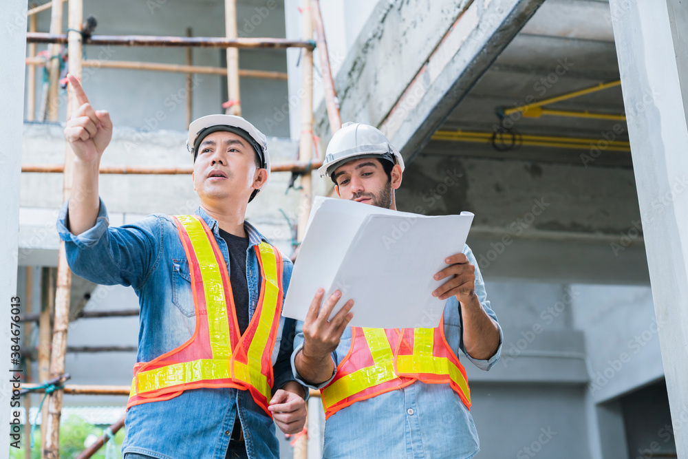 Young Asian engineers and caucasian engineer colleagues at site inspector and discuss together using