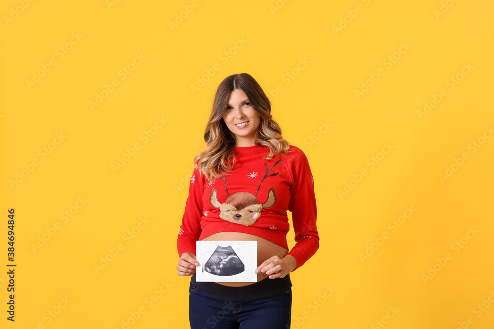 Beautiful pregnant woman with sonogram image on color background. Christmas celebration