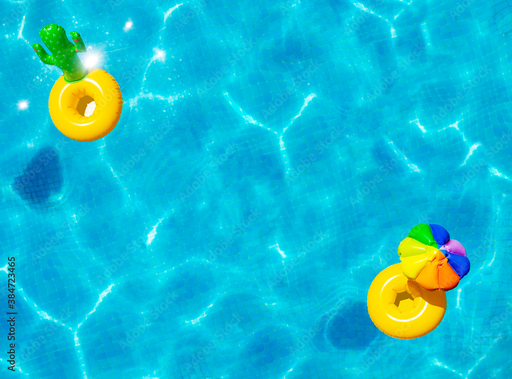 Inflatable yellow sun umbrella and cactus buoys swim in the swimming pool view with perspective