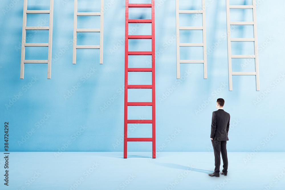 Businessman in suit standing in blue interior and looking on red ladder