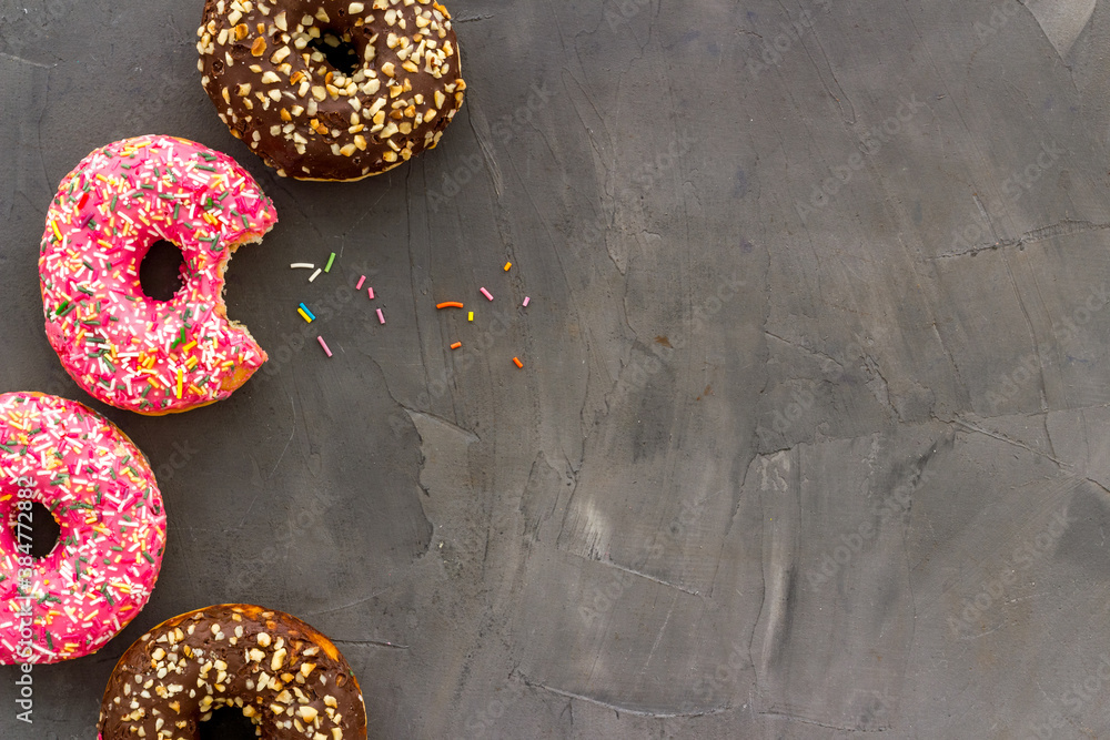 Donuts flat lay pattern on dark background, top view