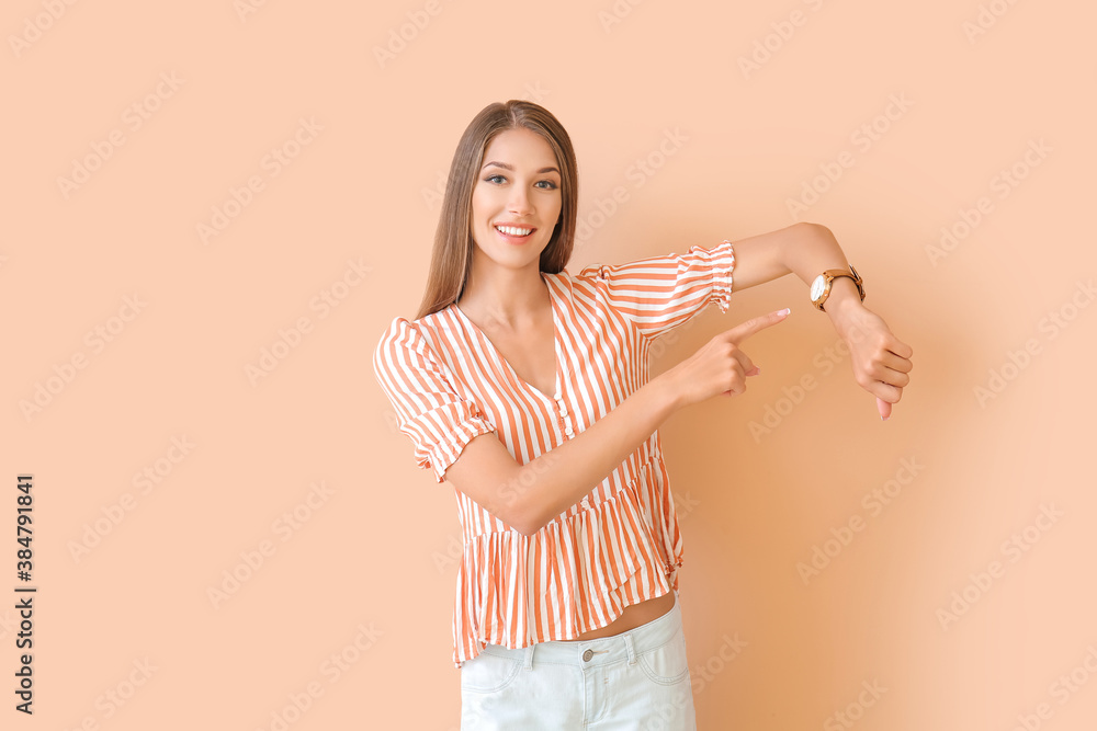 Young woman with wristwatch on color background