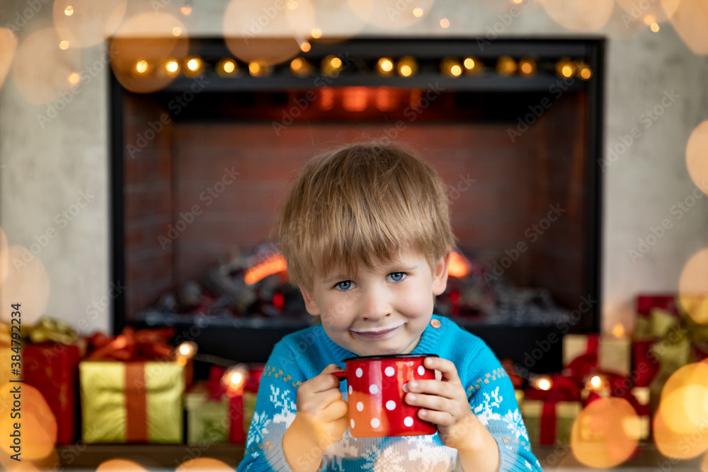 Happy child with cup of milk against fireplace