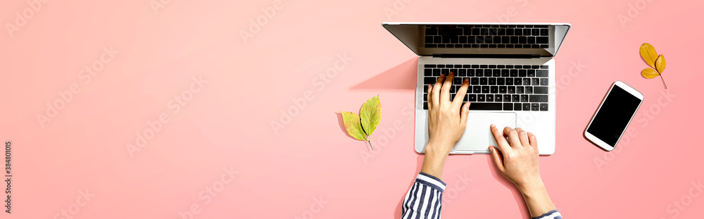 Autumn leaves with person using a laptop computer from above