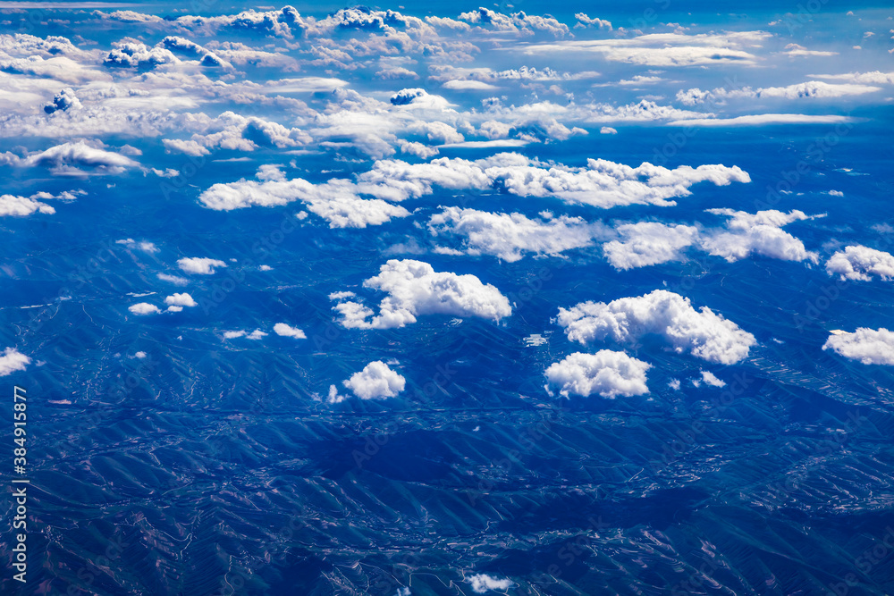 阳光明媚的日子里，云层和山峰上方的鸟瞰图。飞机上的山景。