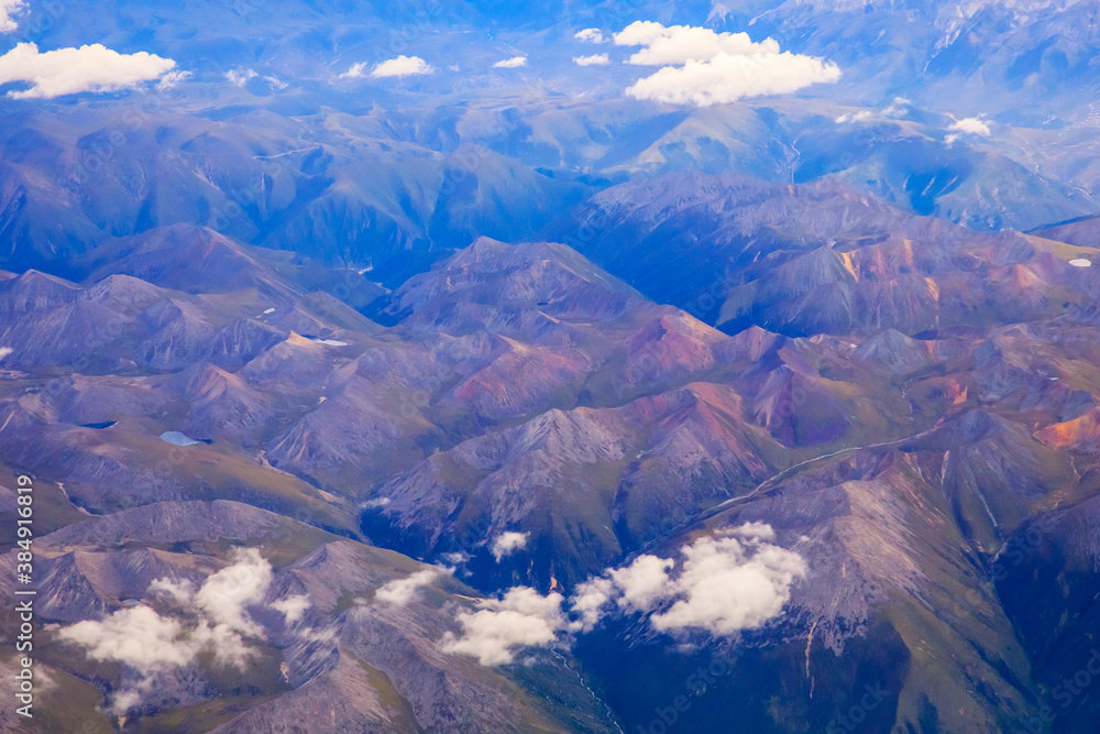 在阳光明媚的日子里俯瞰云朵和山峰。从飞机上俯瞰山景。