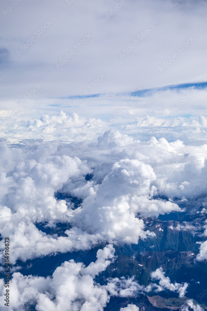 Aerial view above the clouds and mountain peaks on a sunny day.