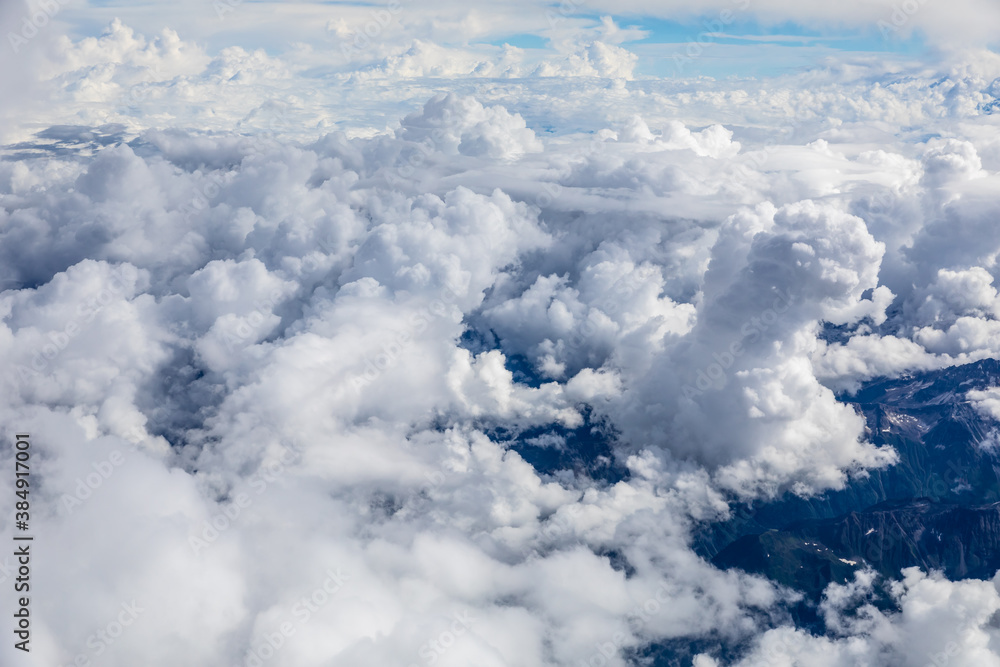 Aerial view above the clouds and mountain peaks on a sunny day.