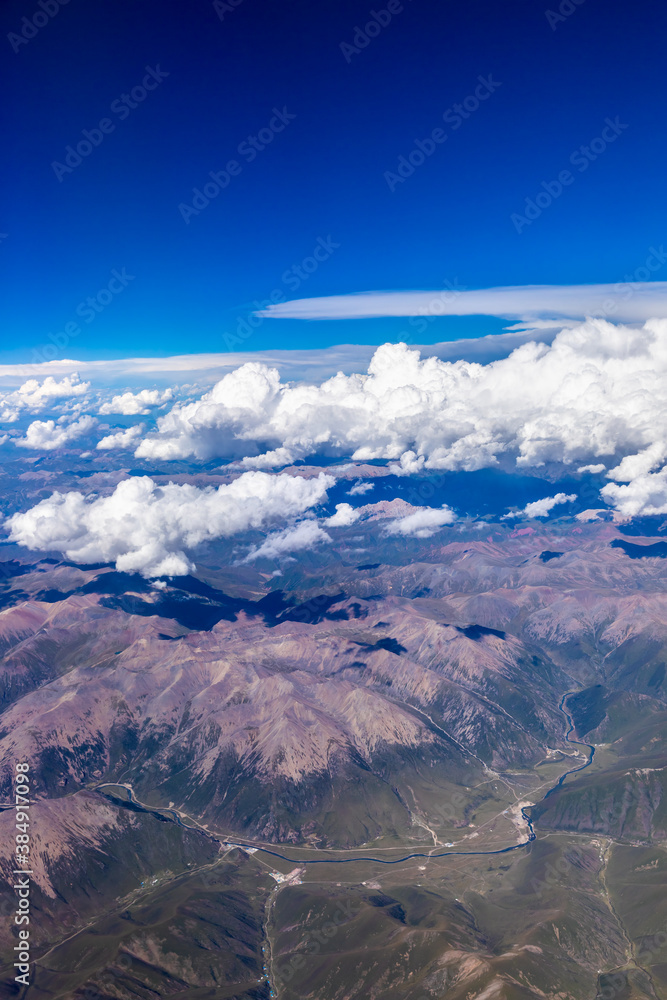 在阳光明媚的日子里俯瞰云朵和山峰。从飞机上俯瞰山景。