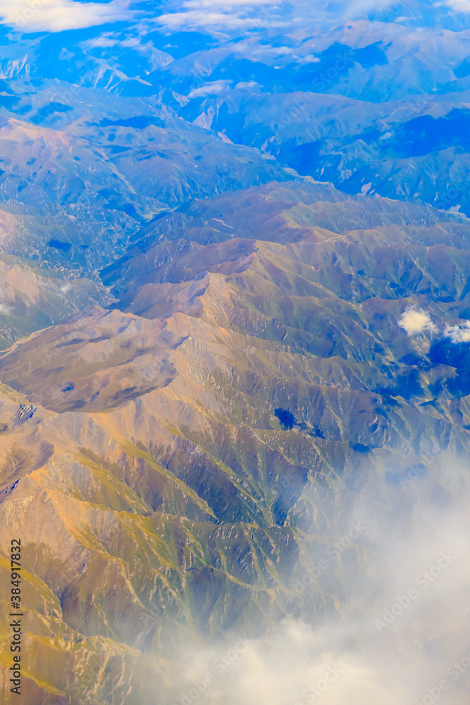 Aerial view above the clouds and mountain peaks on a sunny day.mountain view from airplane.