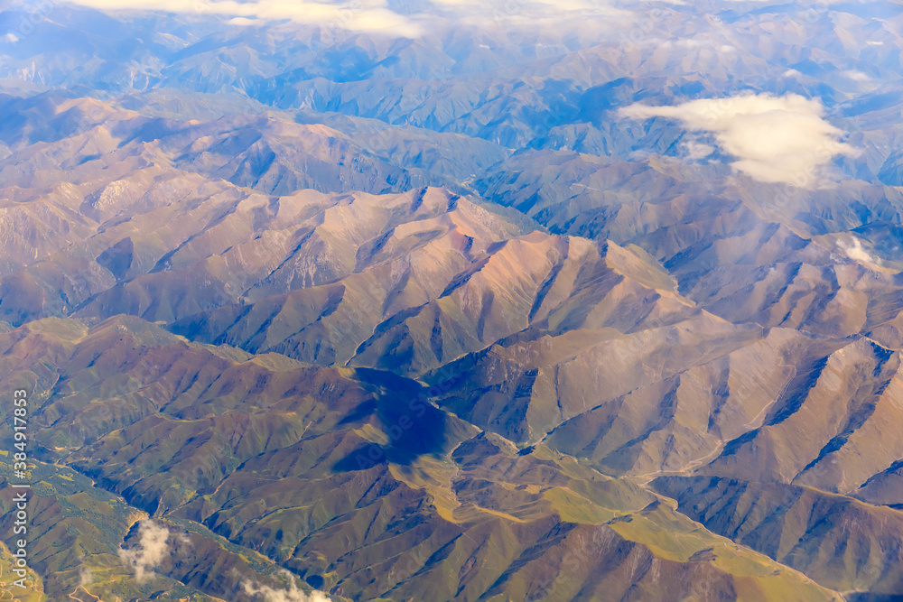 Aerial view above the clouds and mountain peaks on a sunny day.