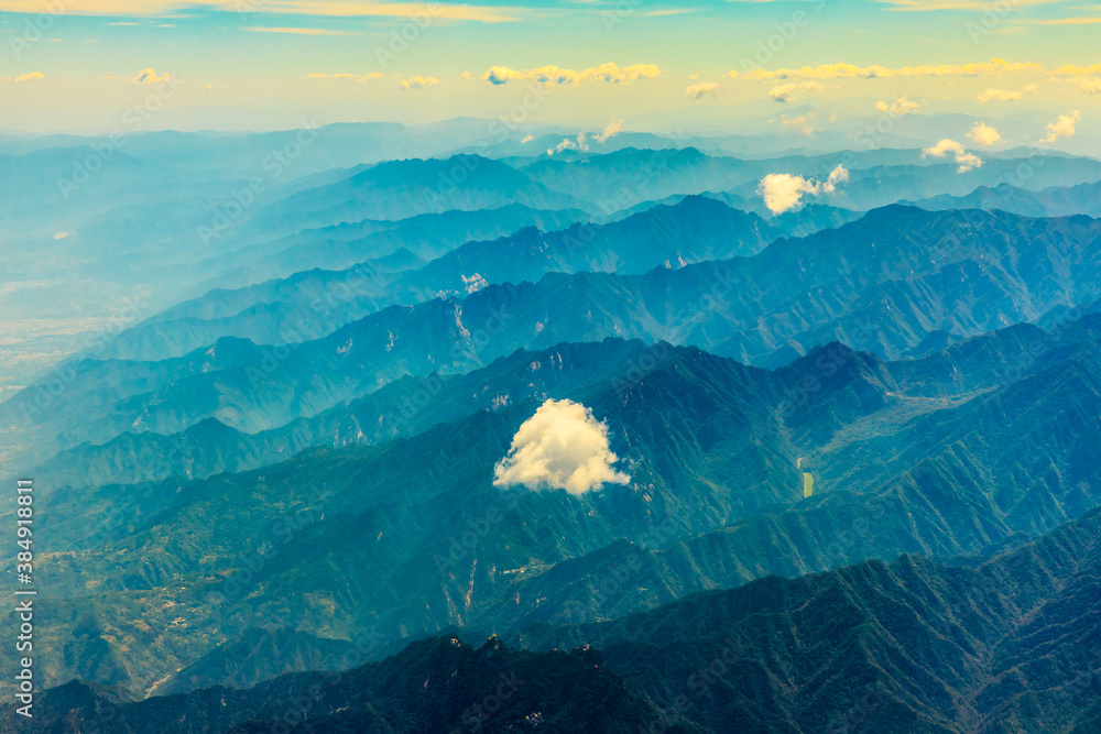 在阳光明媚的日子里俯瞰云朵和山峰。从飞机上俯瞰山景。