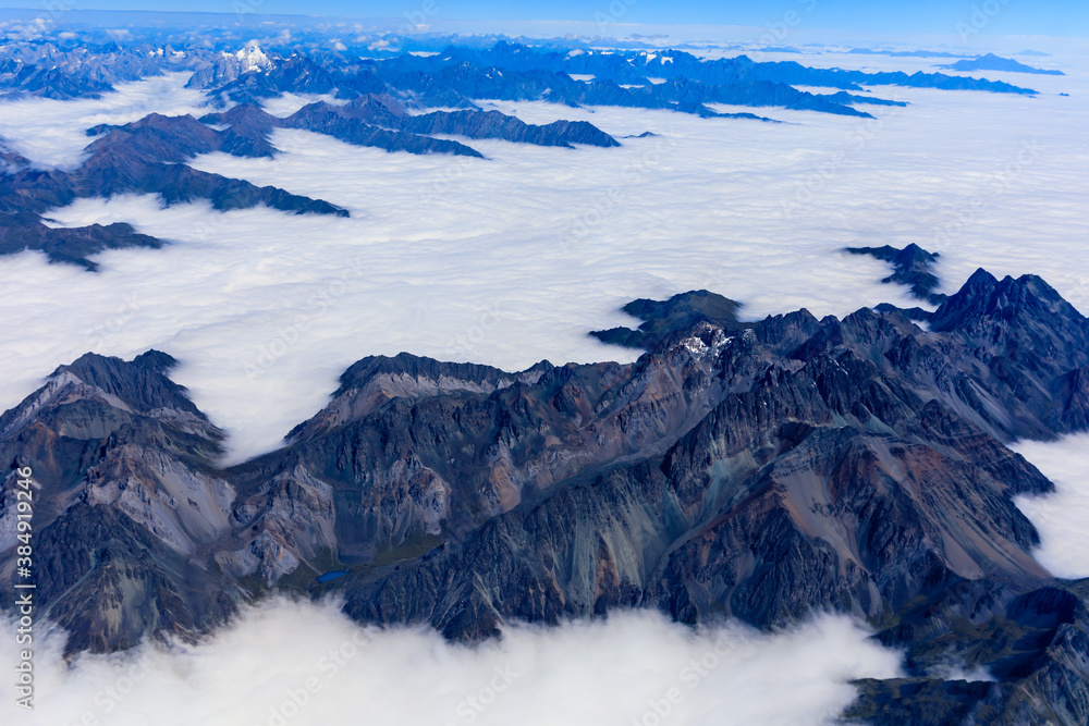 Aerial view above the clouds and mountain peaks on a sunny day.mountain view from airplane.