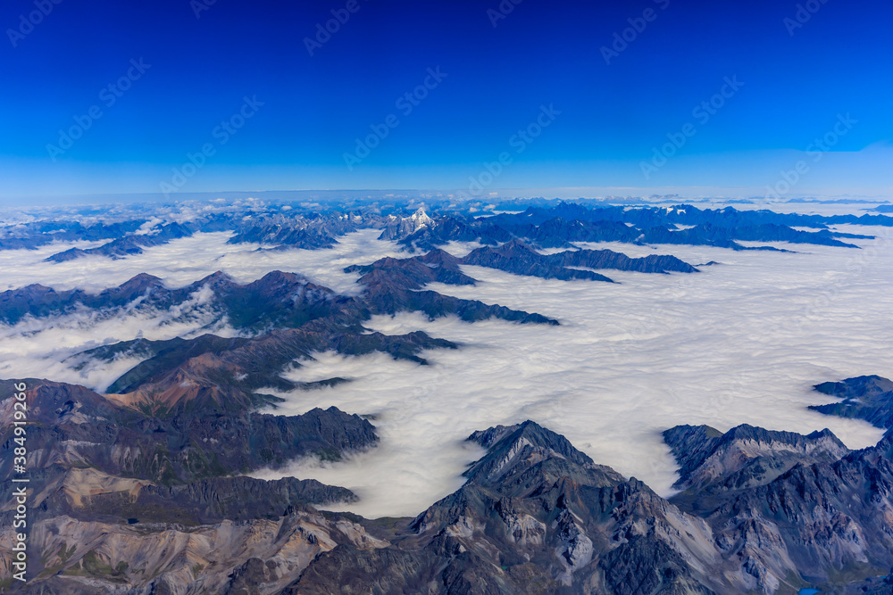 Aerial view above the clouds and mountain peaks on a sunny day.mountain view from airplane.