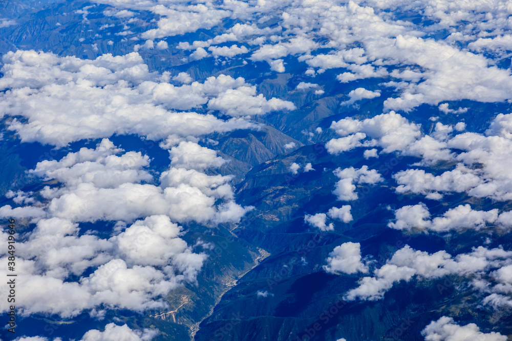 Aerial view above the clouds and mountain peaks on a sunny day.